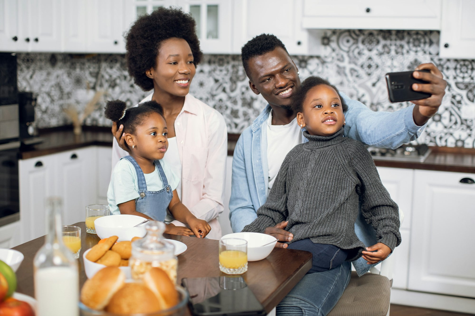 African family using mobile during breakfast on kitchen
