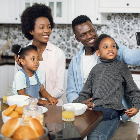 African family using mobile during breakfast on kitchen